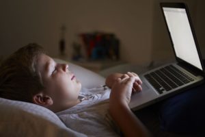 child on computer in bed