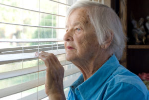 Elderly woman looking out a window.